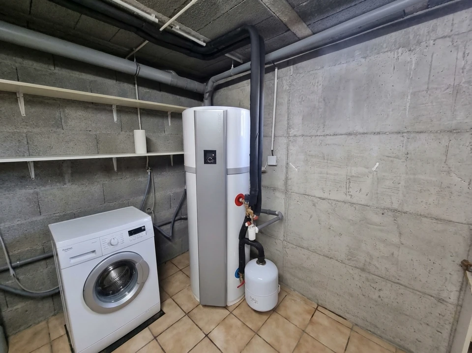 Intérieur de salle de bain moderne avec chauffe-eau électrique mural blanc cylindrique installé dans angle